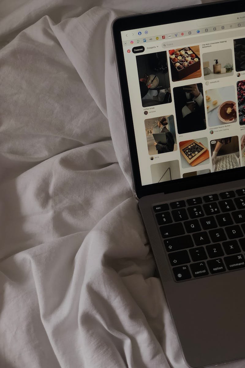 A close-up of a laptop on a bed showing a social media platform.
